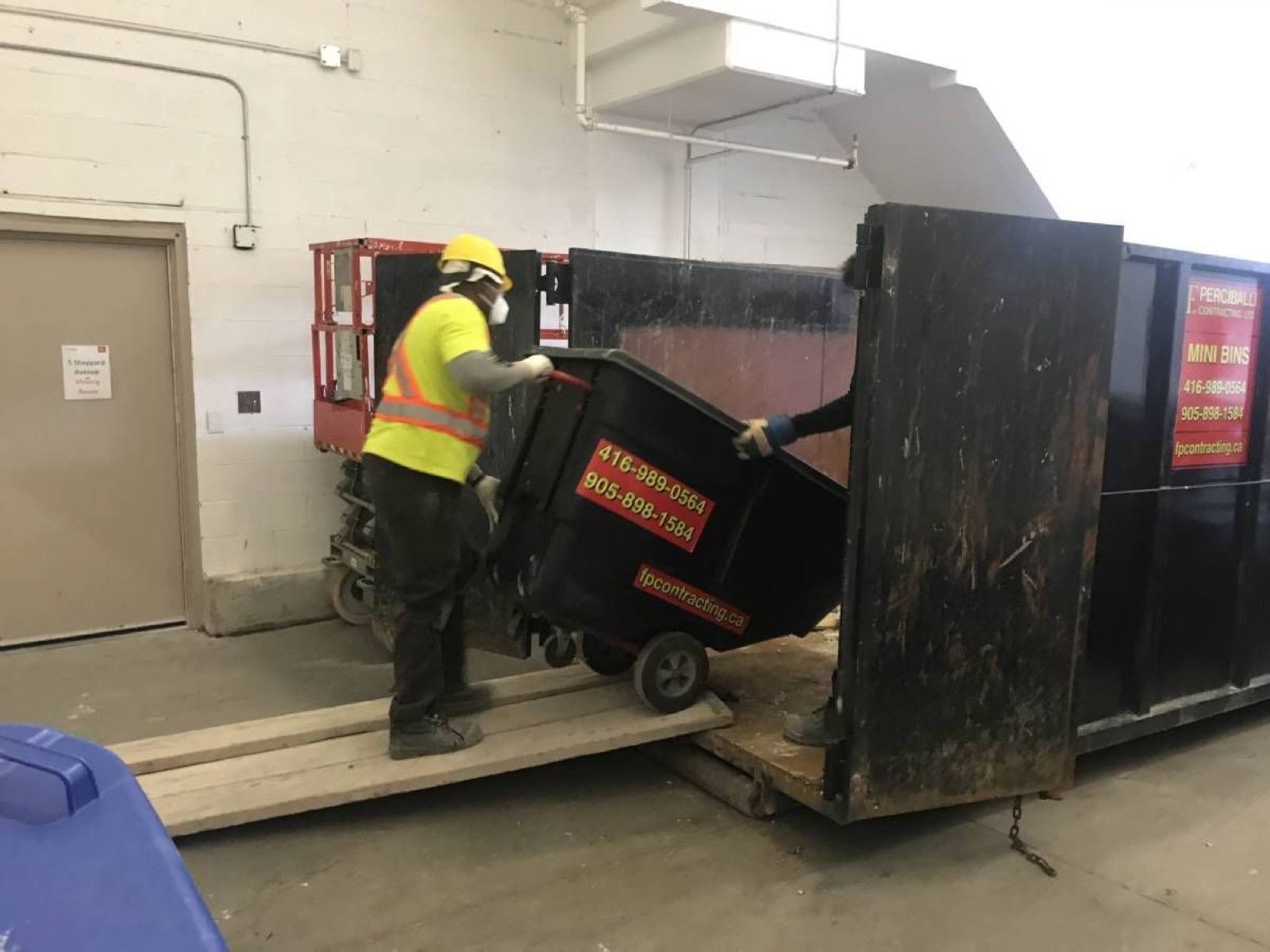 man loading a small bin into a large bin